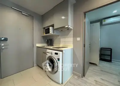 Modern compact kitchen with washing machine and microwave in sleek apartment