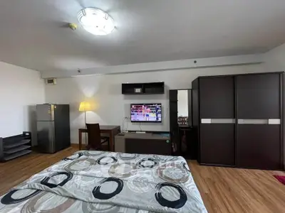 Spacious bedroom with modern decor and wooden flooring, featuring a TV and ample storage space.