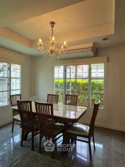 Elegant dining room with chandelier and large windows overlooking garden