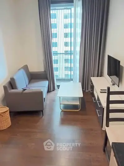 Modern living room with sleek furniture and large window in a high-rise apartment.