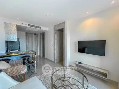 Modern living room with sleek design, featuring a wall-mounted TV, stylish furniture, and an open kitchen layout.