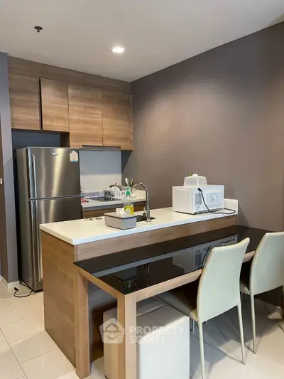 Modern kitchen with sleek design, featuring a stainless steel fridge and microwave, perfect for urban living.