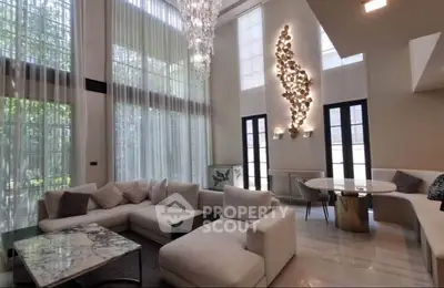 Luxurious living room with high ceilings, elegant chandelier, and modern decor.