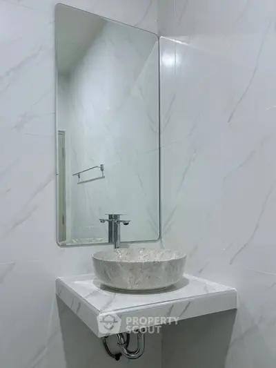Modern bathroom with elegant marble sink and sleek mirror design.