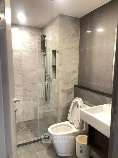 Modern bathroom with sleek gray tiles and glass shower enclosure