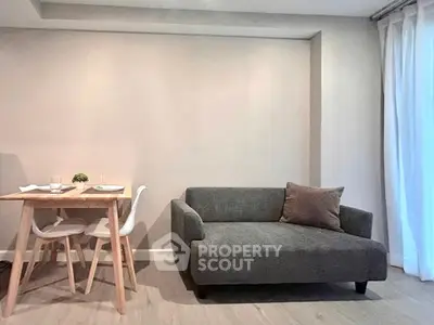 Modern living room with cozy gray sofa and dining table for two.