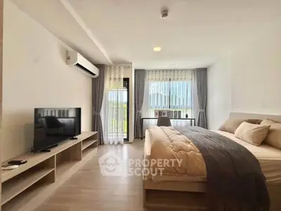 Spacious modern bedroom with large windows and natural light, featuring a cozy bed and sleek TV setup.