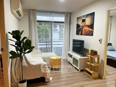 Cozy living room with modern decor and natural light, featuring a TV and stylish furniture.