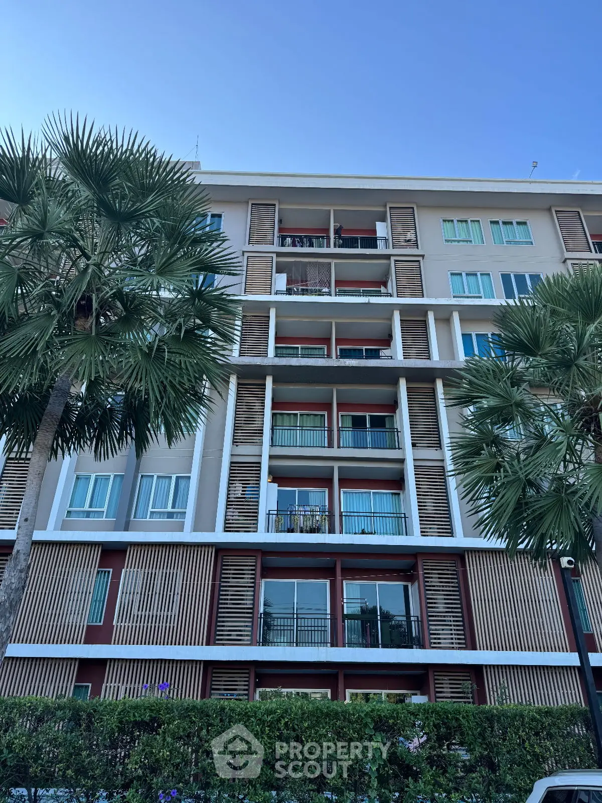 Modern apartment building with lush palm trees and clear blue sky