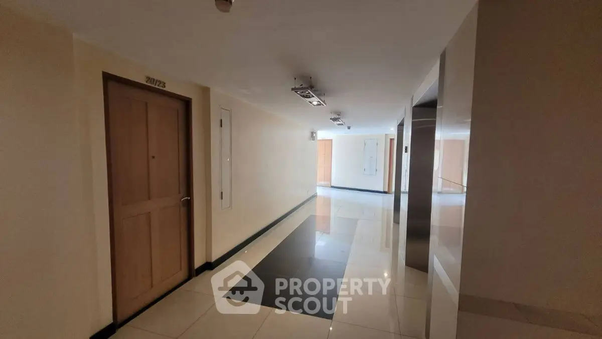Modern apartment hallway with polished tile flooring and wooden doors.