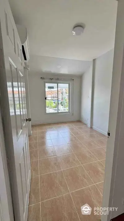 Bright empty room with tiled flooring and large window offering natural light