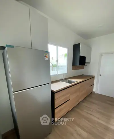 Modern kitchen with sleek cabinetry and stainless steel fridge in bright interior