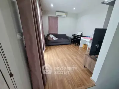 Spacious living room with wooden flooring and modern furnishings in a cozy apartment.