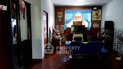 Charming living room with wooden floors and blue accents, featuring a cozy seating area and TV setup.