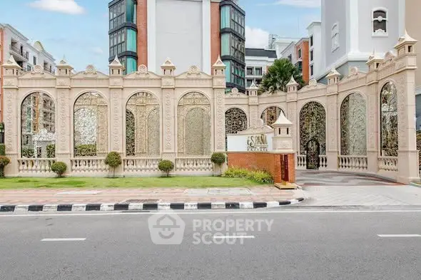 Elegant building entrance with ornate design and lush greenery