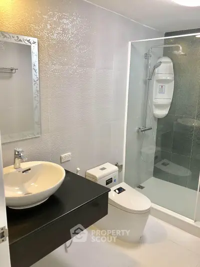 Modern bathroom with sleek fixtures and glass shower enclosure in contemporary apartment.