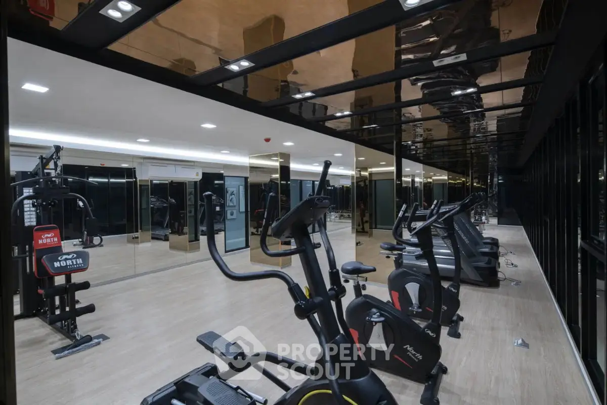 Modern gym with state-of-the-art fitness equipment and mirrored walls in luxury building.