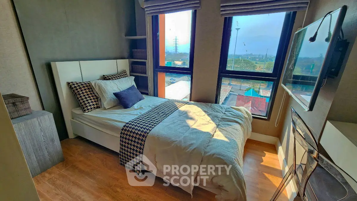 Cozy bedroom with large windows and scenic view, perfect for relaxation.