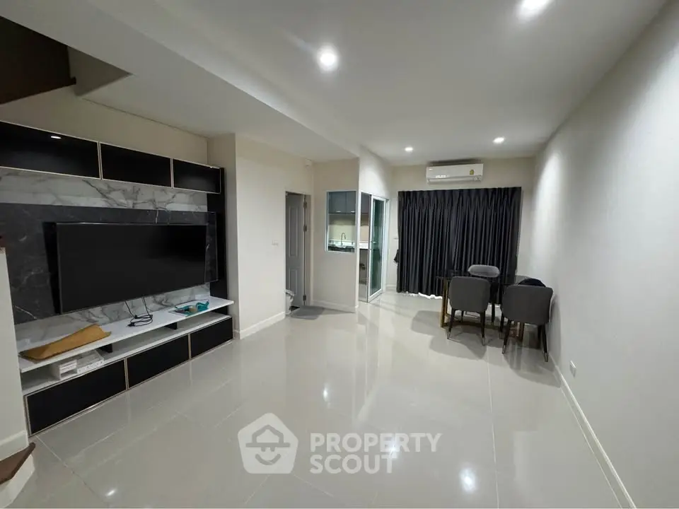 Modern living room with sleek TV unit and dining area, featuring glossy tiled floors and ambient lighting.