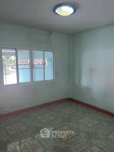 Spacious empty room with tiled floor and large window, perfect for customization.