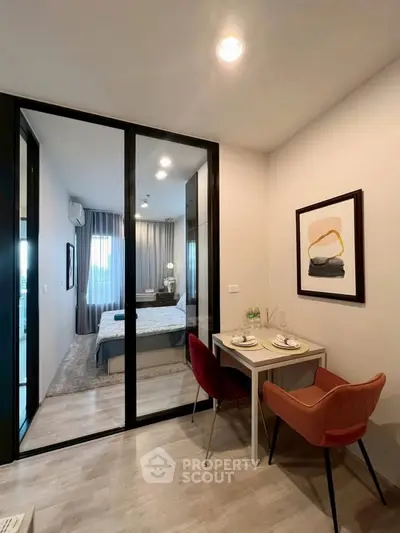 Modern bedroom with glass partition and cozy dining area in stylish apartment.