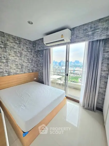 Modern bedroom with city view and balcony access in high-rise apartment
