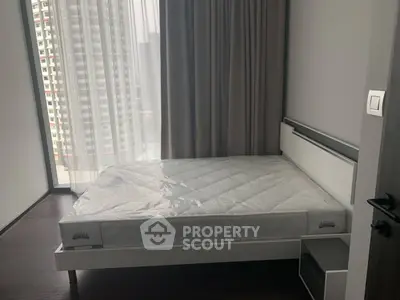 Modern bedroom with large window and city view, featuring a new mattress and sleek design.