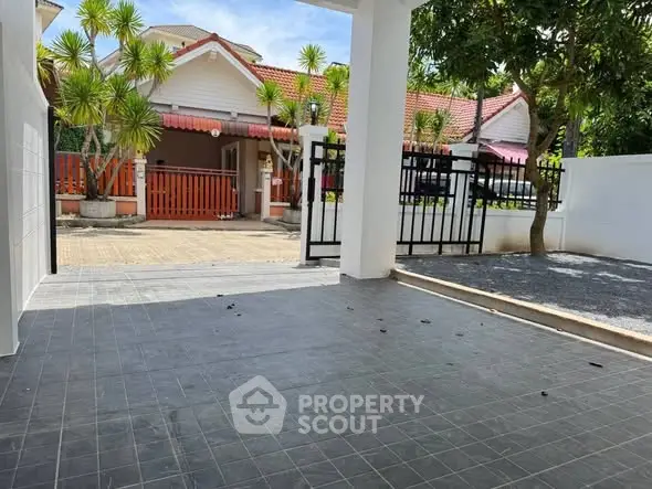 Charming residential entrance with tiled patio and lush greenery