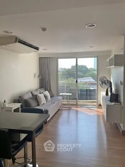 Modern living room with balcony view, featuring sleek furniture and abundant natural light.