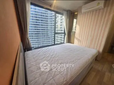 Modern bedroom with large window offering stunning city view in high-rise apartment.