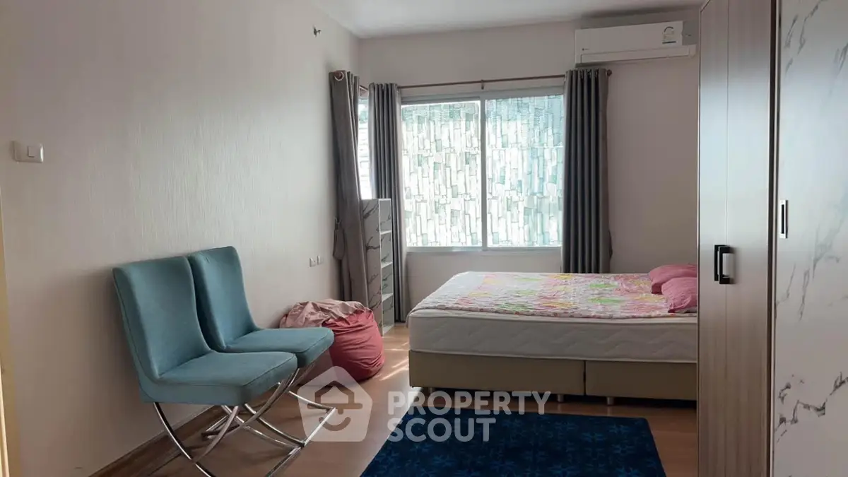 Spacious bedroom with modern furniture and large window for natural light.