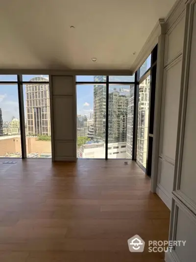 Spacious modern living room with floor-to-ceiling windows and stunning city view.