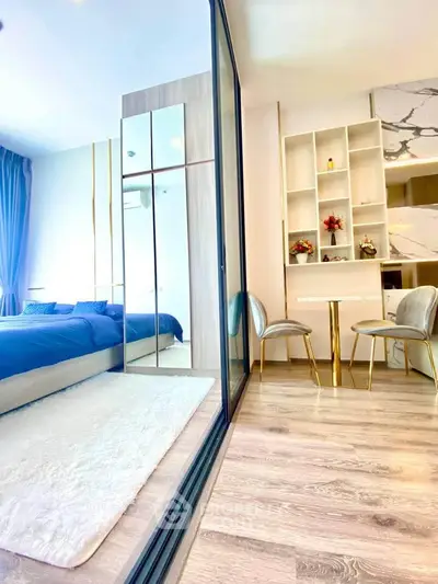 Luxurious bedroom with modern decor and elegant furnishings, featuring a mirrored wardrobe and cozy seating area.