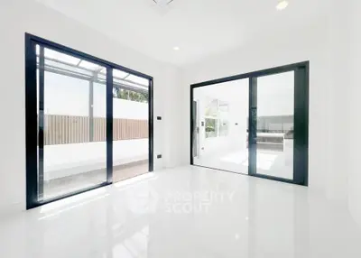 Bright modern living room with large sliding glass doors and sleek white flooring.