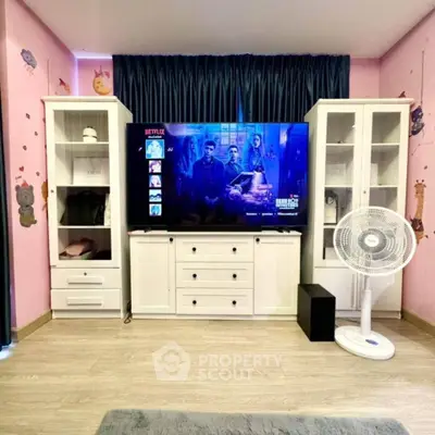 Charming living room with stylish white furniture and large TV setup.