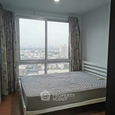 Spacious bedroom with large window offering stunning city views.