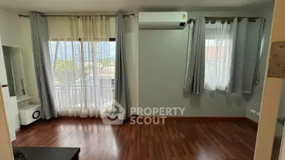 Spacious living room with hardwood floors and large windows offering natural light.