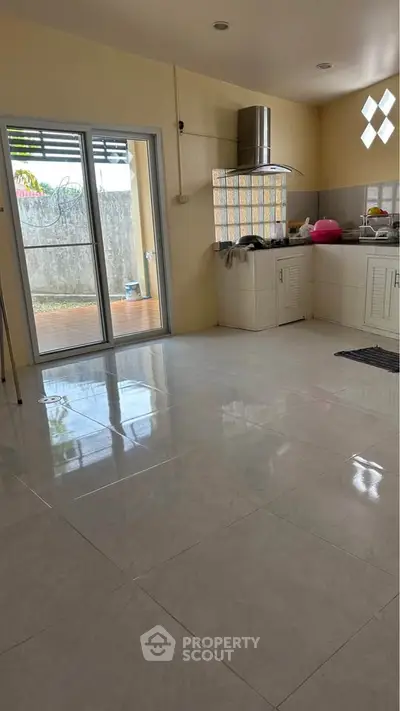 Spacious kitchen with open layout and modern appliances, featuring a sliding door to the outdoor area.