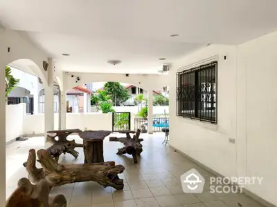 Spacious covered patio with unique wooden furniture and pool view