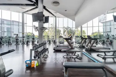Spacious modern gym with large windows and fitness equipment