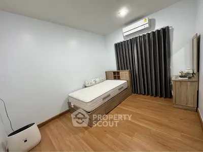 Spacious bedroom with modern wooden flooring and air conditioning