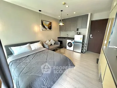 Modern studio apartment with cozy bed, compact kitchen, and washing machine.