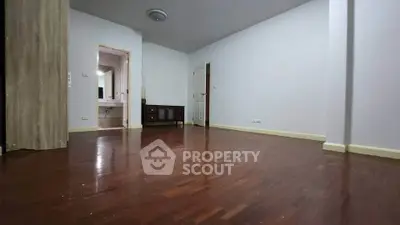 Spacious empty room with wooden flooring and neutral walls, ideal for customization.