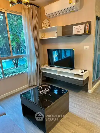 Modern living room with sleek furniture and large window overlooking greenery.