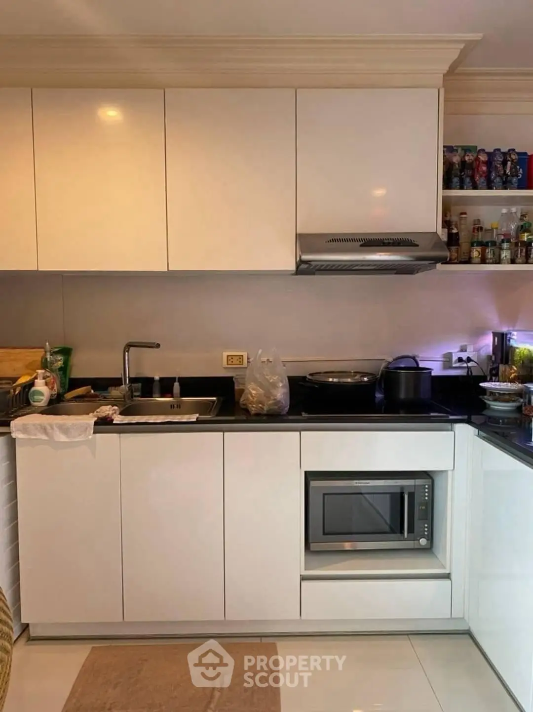 Modern kitchen with sleek white cabinets and built-in microwave, perfect for culinary enthusiasts.