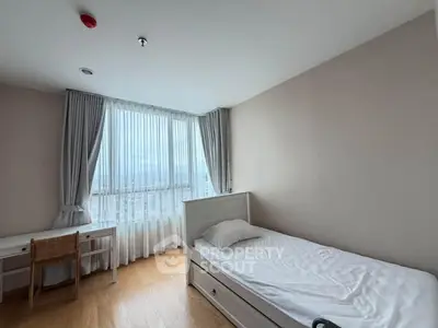 Bright bedroom with single bed, desk, and large window with city view.