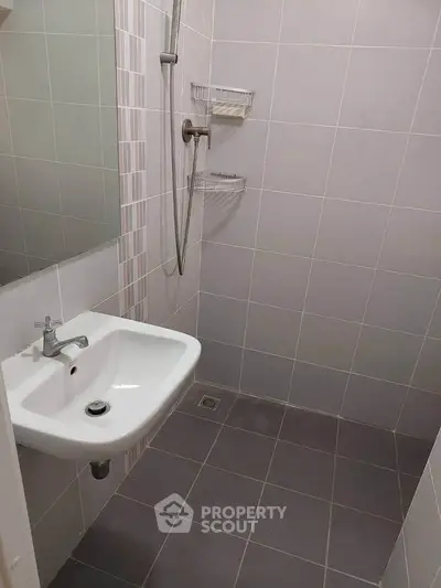 Compact bathroom with modern shower and sink, ideal for efficient space use.