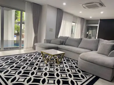Spacious living room with modern gray sofa and stylish geometric rug, featuring large windows for natural light.