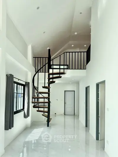 Modern duplex interior with spiral staircase and high ceilings