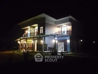 Stunning modern two-story house with illuminated exterior at night, featuring spacious balconies and sleek design.